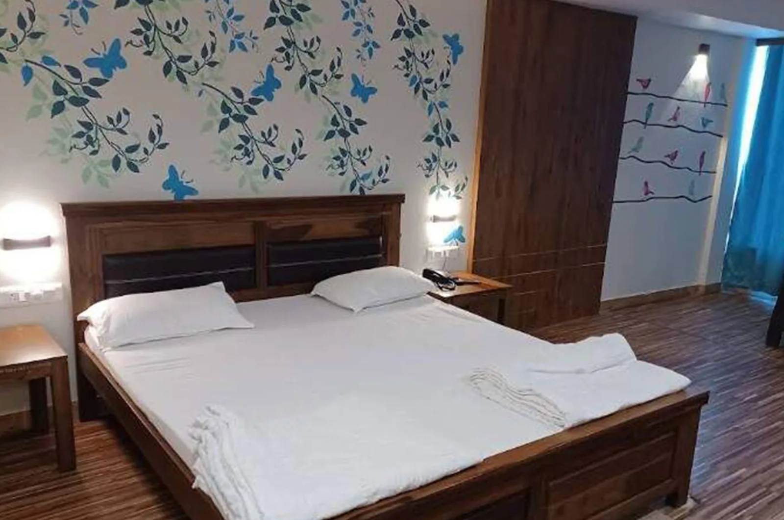 Super Deluxe Room with a double bed made up in white linen and a wooden floor