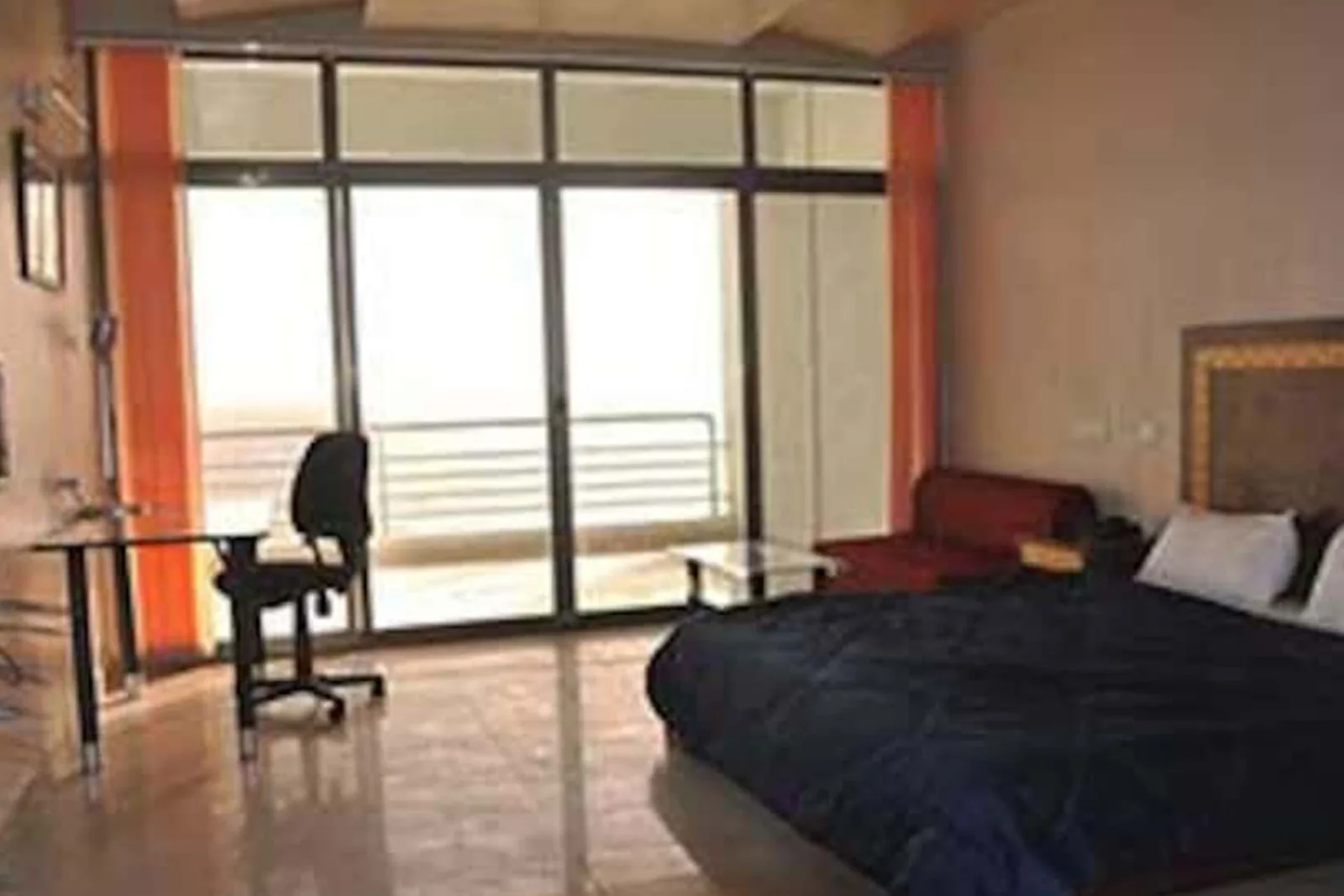 Sea facing room with a bed, a work desk and chair, and full height glazing onto the balcony